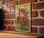 A vintage-style stamp depicting red flowers is mounted on a brick wall, with a wooden table below it.