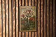 A vintage-style stamp featuring a floral illustration of a honeysuckle flower, mounted on a wooden wall.