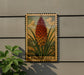A framed illustration of a kniphofia flower is displayed on a wall, with a plant to the left of the frame.