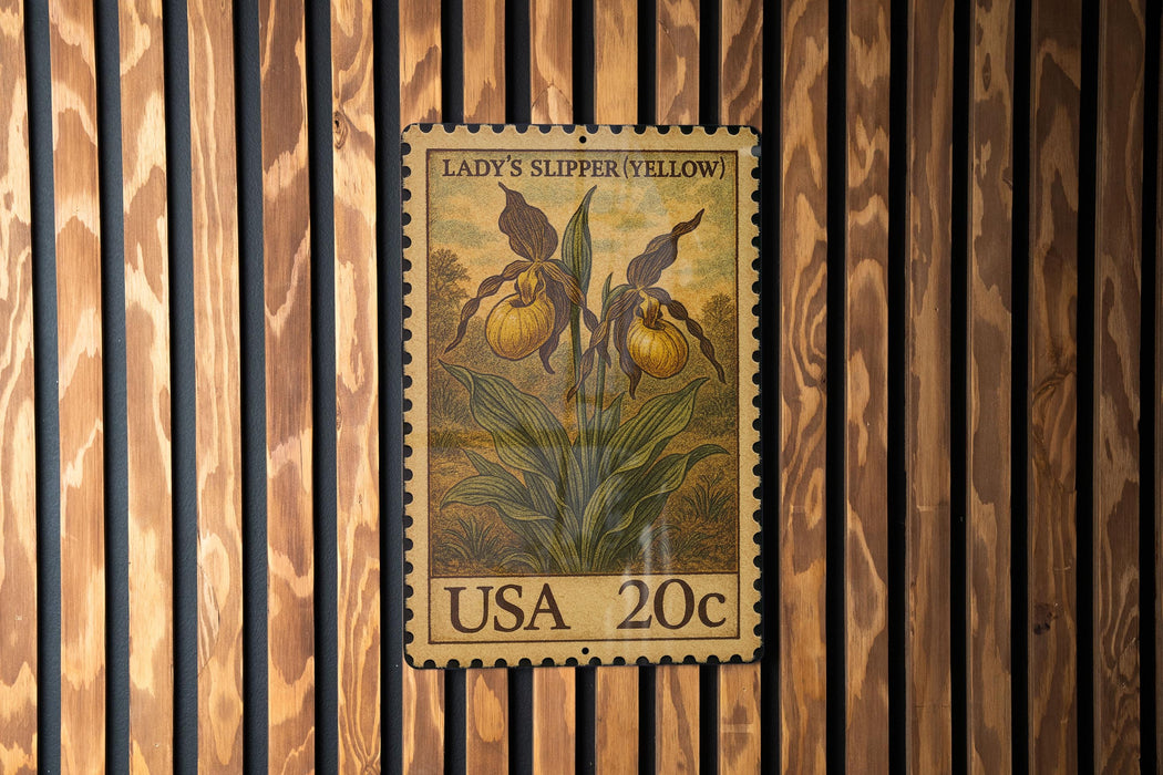 A vintage 20c US postage stamp featuring a yellow orchid plant is displayed on a wooden wall.