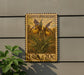 A postage stamp featuring a yellow flower with green leaves, mounted on a wall next to a plant.