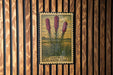 A framed illustration of three pink flowers is displayed on a wooden wall.