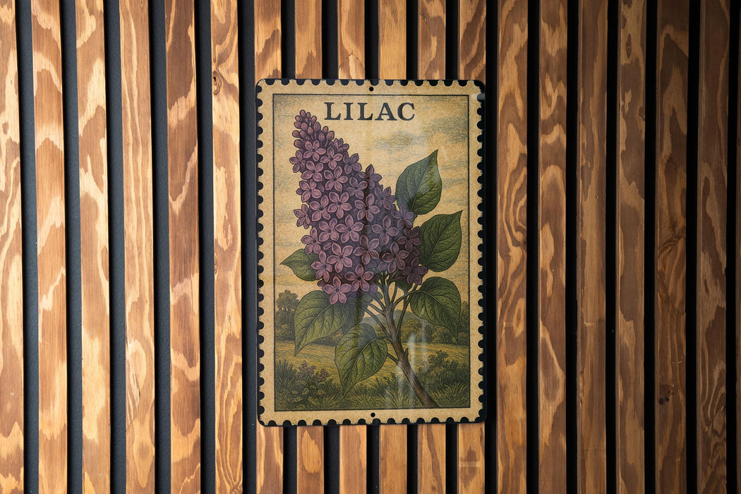 A vintage-style postage stamp featuring a close-up of a purple lilac flower is displayed on a wooden wall.