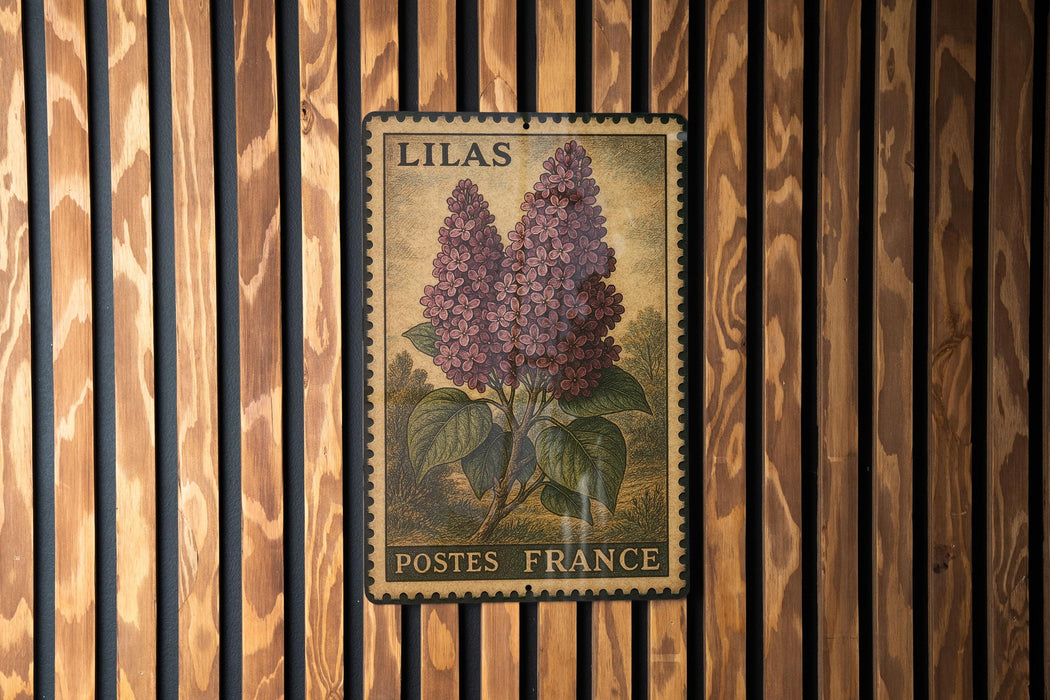 A vintage postage stamp featuring a depiction of purple lilac flowers, mounted on a wooden wall.