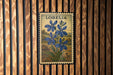 A postage stamp from Lobelia, featuring a blue flower, is displayed on a wooden wall.