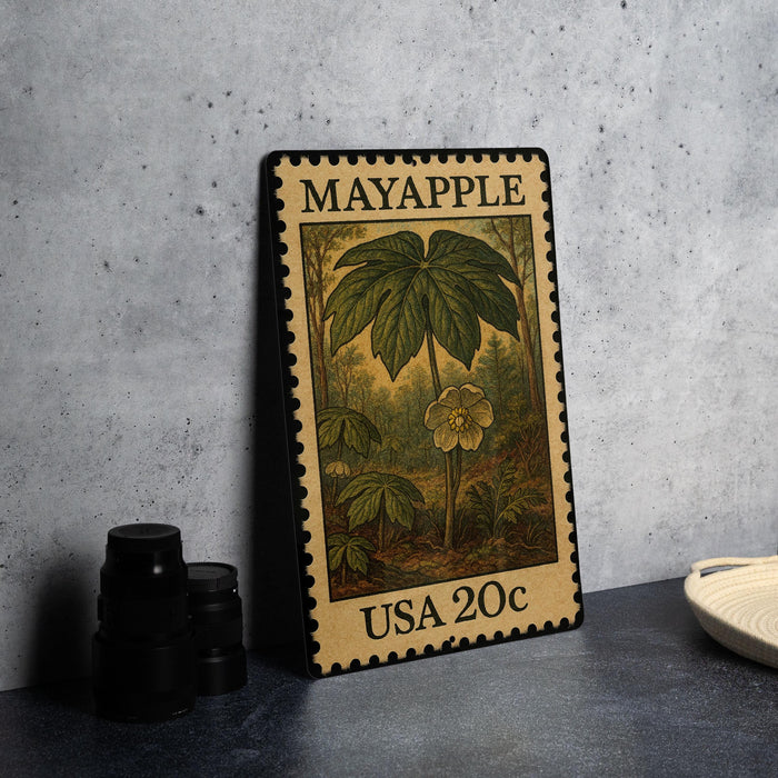 A metal stamp with a floral design and text, placed on a table next to some black camera lenses.