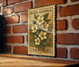A vintage-style postage stamp featuring a floral design is displayed on a brick wall.