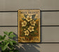 A postage stamp featuring a floral design is mounted on a wall, with a plant visible to the left.