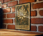 A metal sign with a floral design is mounted on a brick wall.