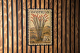 A postage stamp from the United States of America, featuring a desert plant with red flowers, mounted on a wooden wall.