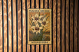 A metal plaque with a floral design hangs on a wooden wall.