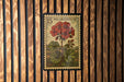 A framed image of a red flower on a wooden wall.