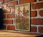 A framed illustration of a penstemon flower is displayed on a brick wall, with a wooden table below it.