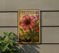 A wooden postcard with a large red flower and green leaves, mounted on a wall next to a plant.