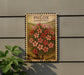 a wooden sign with a floral design, mounted on a wall next to a plant.