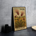 A framed postage stamp depicting a field of flowers, specifically Prairie Smoke, is displayed on a table.
