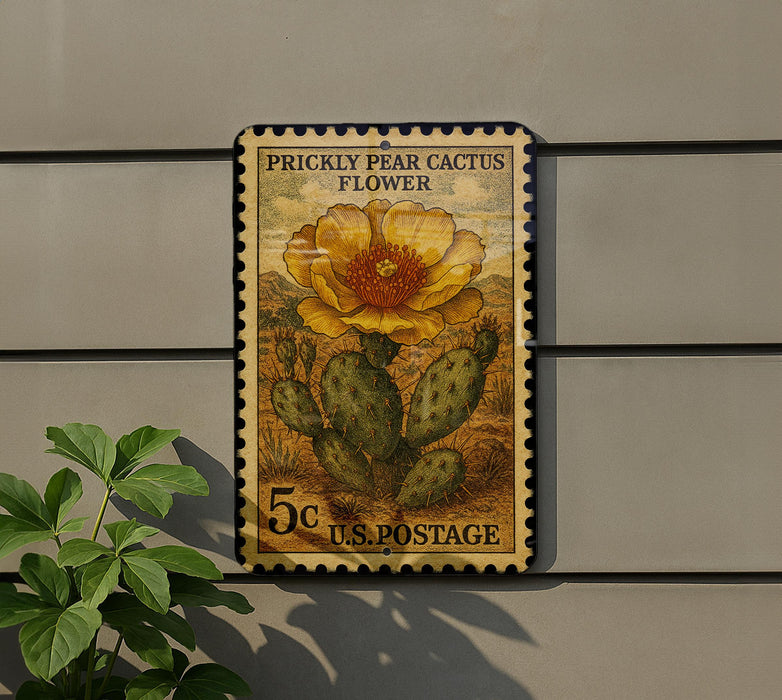 A postage stamp featuring a prickly pear cactus flower, mounted on a wall next to a plant.