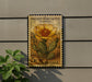 A postage stamp featuring a prickly pear cactus flower, mounted on a wall next to a plant.