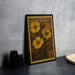 A vintage-style postage stamp featuring a yellow flower design, placed on a dark surface next to some black camera lenses.