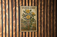 A framed illustration of a plant with yellow flowers is hanging on a wooden wall.