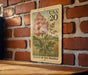 A wooden table with a brick wall in the background, featuring a framed image of a flower with the text "USA 20" and "QUEEN OF THE PRAIRIE" printed on it.