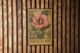 A vintage-style metal sign with a floral illustration and the text "ROSE OF SHARON" is displayed on a wooden wall.