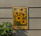 A postage stamp featuring a vibrant yellow sunflower is displayed on a wall, with a plant to the left.