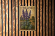 A framed botanical illustration of purple flowers is displayed on a wooden wall.