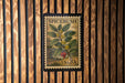 A framed stamp from the United States, featuring an illustration of a plant with red berries and green leaves, mounted on a wooden wall.