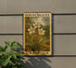 A vintage-style postage stamp featuring a floral design, mounted on a wall next to a plant.