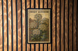 A framed illustration of a flower is hanging on a wooden wall.