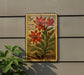 A 5c postage stamp featuring a red flower and green leaves, mounted on a wall next to a plant.
