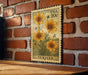 A vintage-style postage stamp featuring a floral design with yellow flowers is displayed on a brick wall.
