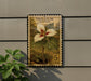 A framed image of a white trillium flower, which is a type of wildflower, is mounted on a wall.
