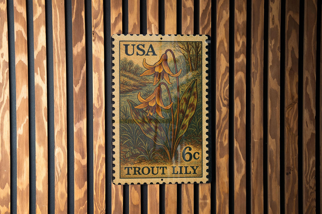 A U.S. postage stamp featuring a lily flower is displayed on a wooden wall.