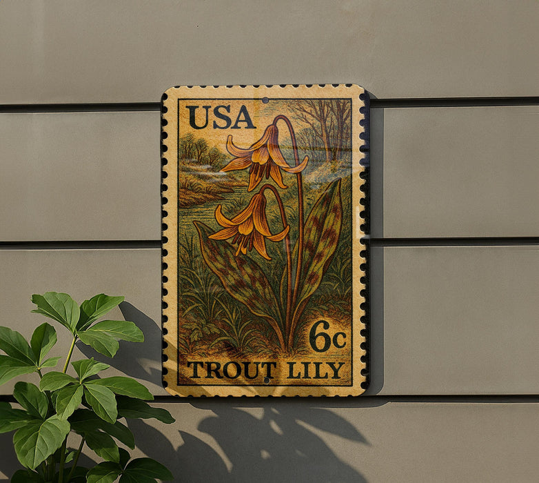 A postage stamp featuring a lily flower is displayed on a wall, with a plant to the left.