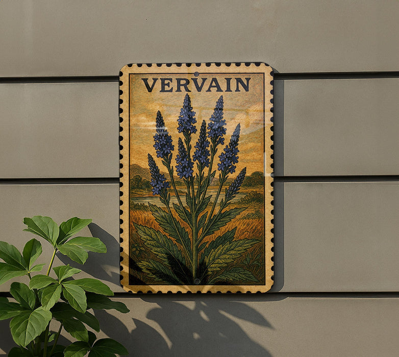 a framed illustration of blue flowers on a wall, with a plant to the left of the frame.