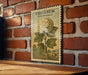 A vintage postage stamp featuring a snowball plant is displayed on a brick wall.
