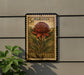 A 5d Waratah postage stamp from Australia is displayed on a wall, with a plant to the left of the stamp.