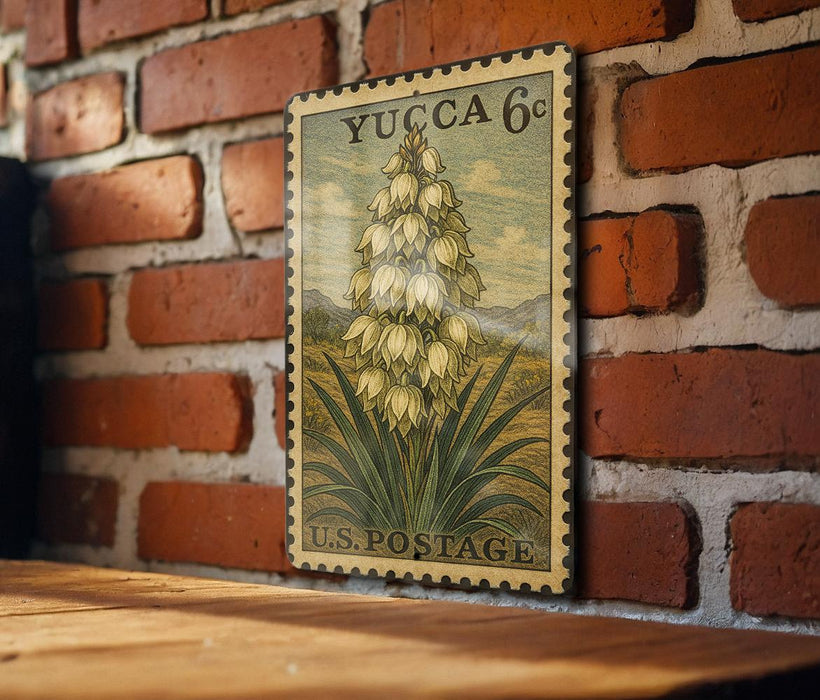 A vintage Yucca 6c postage stamp featuring a detailed illustration of a flower is displayed on a brick wall.
