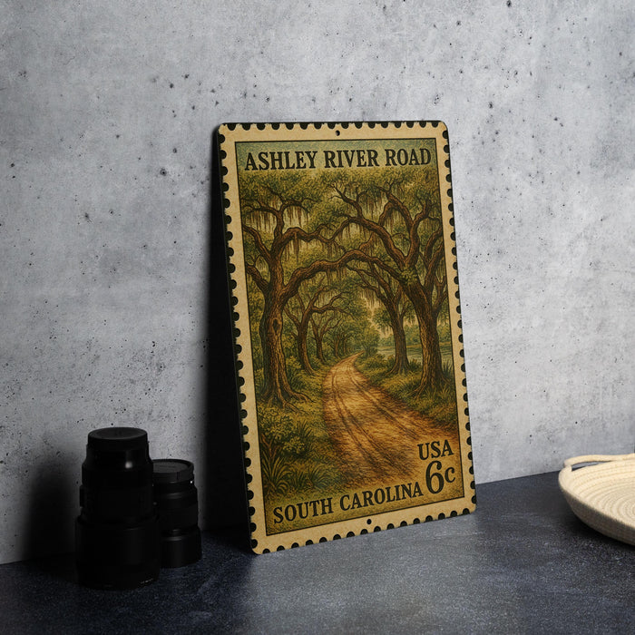 A metal stamp depicting a scenic road through a forest, with the text "ASHLEY RIVER ROAD" and "SOUTH CAROLINA" printed on it.
