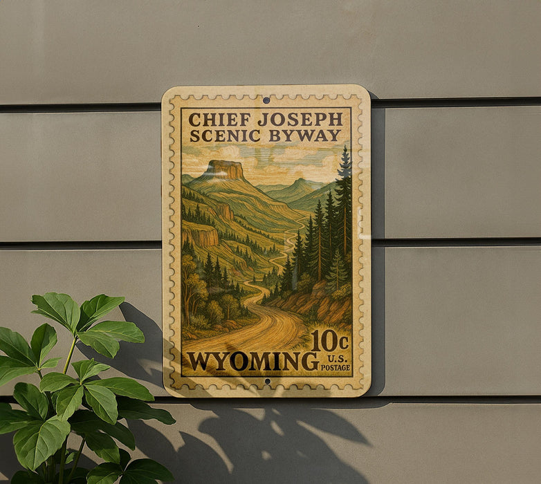 A 10-cent U.S. postage stamp from Wyoming, featuring a scenic mountain landscape, is displayed on a wall next to a plant.