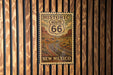 A vintage-style poster of the historic Route 66 in New Mexico, featuring a winding road and desert landscape.