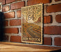 A vintage-style sign for the Historic Route 66 in New Mexico, featuring a desert landscape and a road.