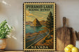 A framed vintage-style poster of Pyramid Lake, Nevada, depicting a scenic road leading to a mountain island, is displayed on a shelf next to a wooden cutting board and a potted plant.