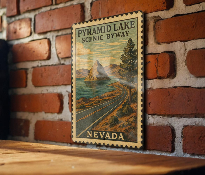 A vintage-style postage stamp depicting the Pyramid Lake scenic byway in Nevada, hanging on a brick wall.
