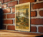 A metal sign with a scenic illustration of Maine's Rangeley Lakes byway, mounted on a brick wall.