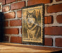 A framed image of a husky dog, likely an Alaskan Malamute, is displayed on a brick wall.