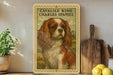 a framed illustration of a Cavalier King Charles Spaniel dog, with a potted plant to the left and a wooden cutting board to the right.