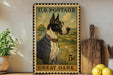 A framed postage stamp featuring a Great Dane dog, placed on a shelf next to a wooden cutting board and some lemons.
